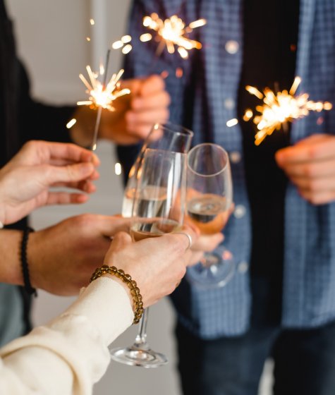 Christmas revellers hold sparklers and glasses of champagne Image