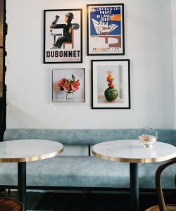 The interior of La Lune bar features light blue velvet booths with small round, white marbled and gold-edged tables