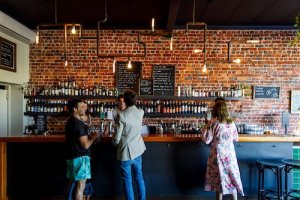 Mrs Brown bar has exposed brick walls, pendant warm lights, and a large bar stocked with liquor bottles