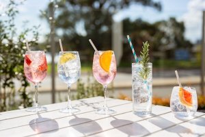 A picnic table with five glasses of fruity cocktails