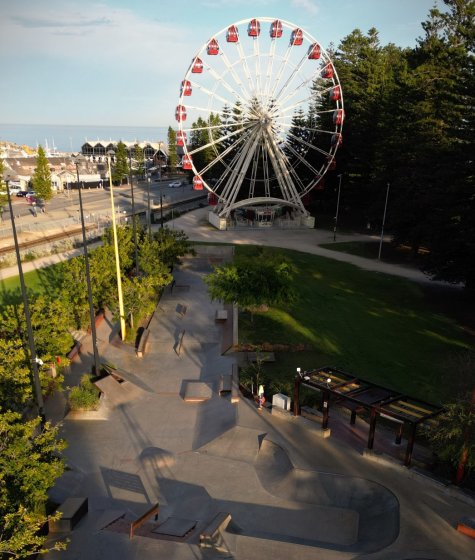 A beachfront park with a ferris wheel and skate park area Image