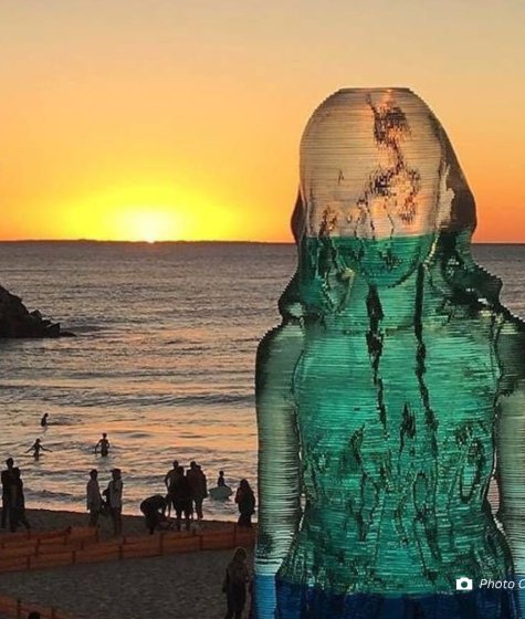 transparent sculpture of a woman that overlooks the beach at sunset Image