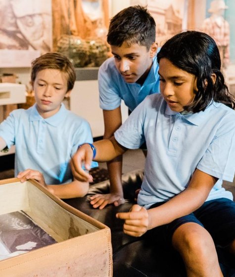 schoolchildren looking through an old suitcase at an educational exhibit at the wa maritime museum Image